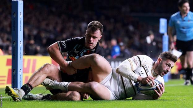 Jonny May rolls over the line with the ball while being tackled to score a try for Gloucester against Harlequins