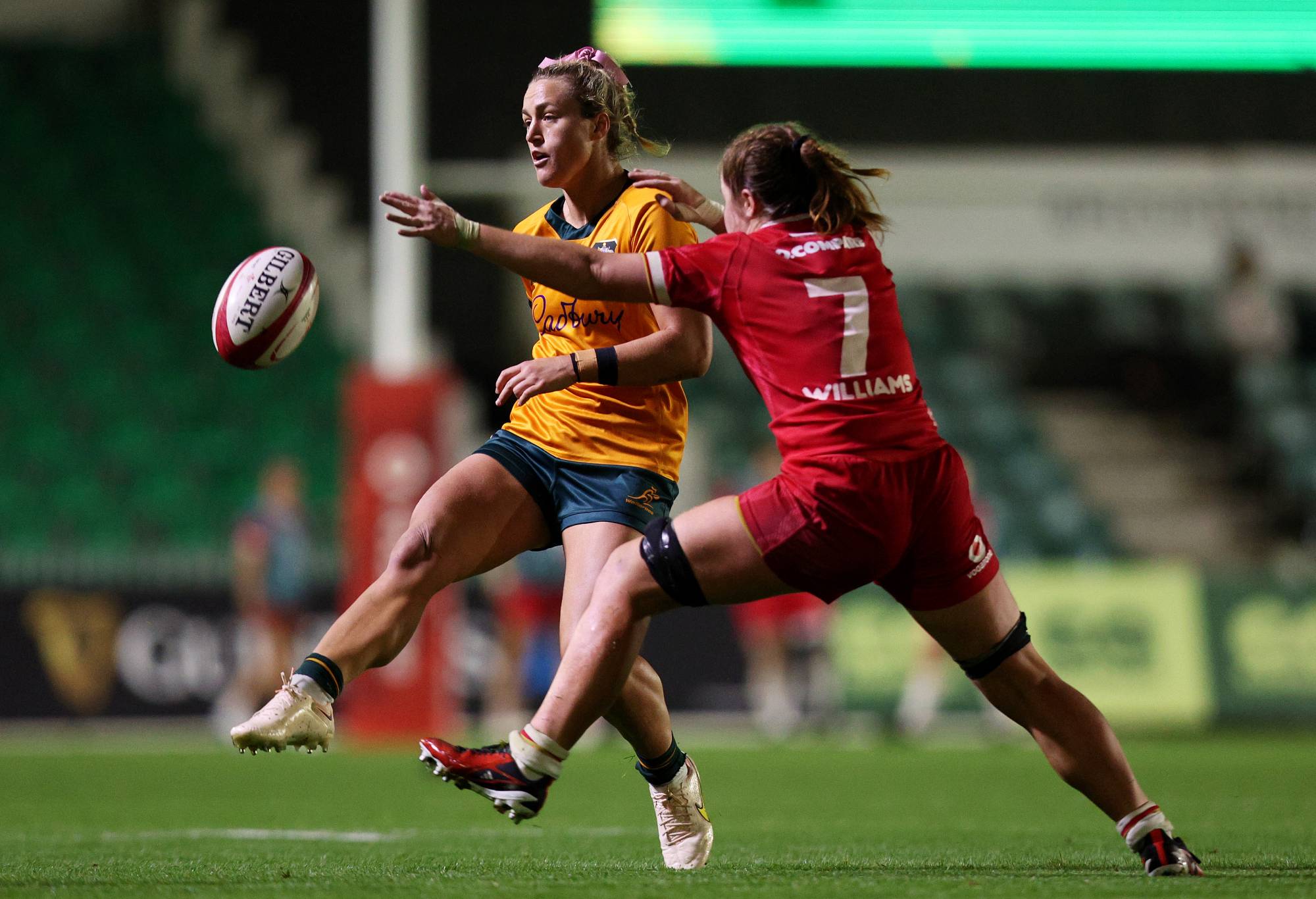 NEWPORT, WALES - SEPTEMBER 20: Arabella McKenzie of Australia chip kicks the ball past Kate Williams of Wales during the Women's International Test Match between Wales and Australia Wallaroos at Rodney Parade on September 20, 2024 in Newport, Wales. (Photo by Ryan Hiscott/Getty Images)