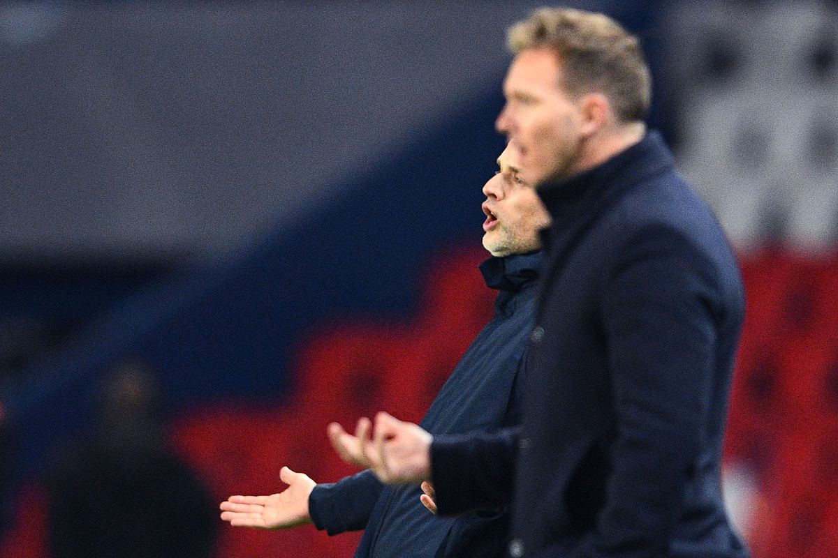 Julian Nagelsmann (foreground, blurry) and Thomas Tuchel (background) react from the sidelines in a Champions League match between PSG and RB-Leipzig.